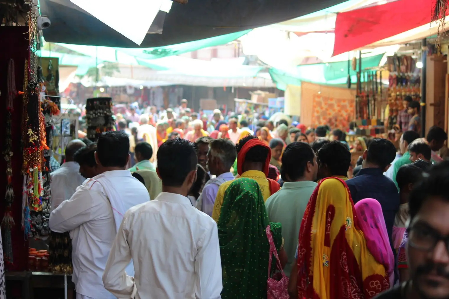 A crowded market street in a small Indian town, with shoppers and stalls selling colourful clothes