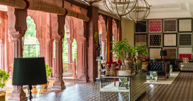 Lobby of a heritage hotel in Bikaner, Rajasthan, with red sandstone arches, a central counter and a lamp in the foreground
